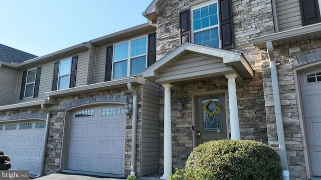 doorway to property with a garage and stone siding