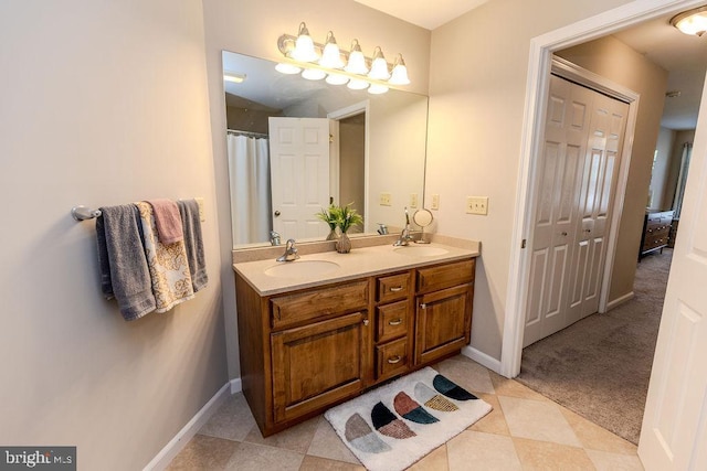 bathroom with double vanity, baseboards, tile patterned flooring, and a sink