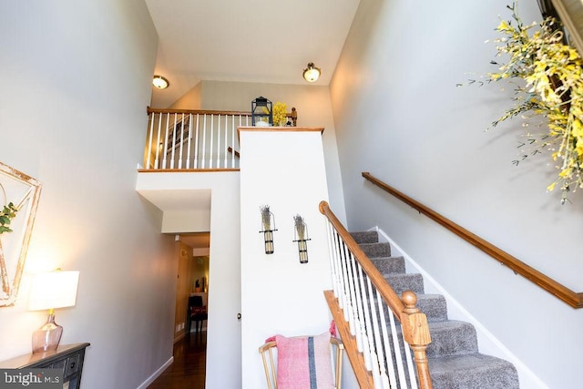 staircase with wood finished floors, baseboards, and a high ceiling