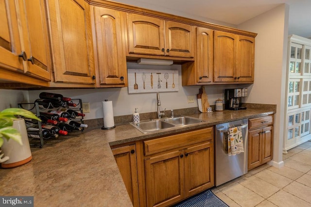 kitchen featuring brown cabinets, dark countertops, dishwasher, a sink, and light tile patterned flooring