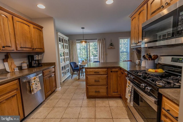 kitchen featuring brown cabinetry, stainless steel appliances, dark countertops, and recessed lighting