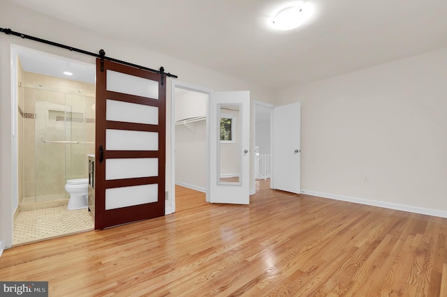 9235 E Parkhill Dr, Bethesda, MD 20814 - unfurnished bedroom featuring a barn door, light wood-style flooring, a closet, and baseboards