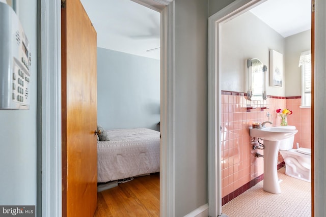 bathroom featuring tile patterned floors, ensuite bath, a wainscoted wall, and tile walls