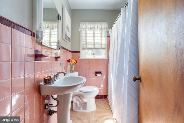 full bath with tile patterned floors, a wainscoted wall, toilet, and tile walls