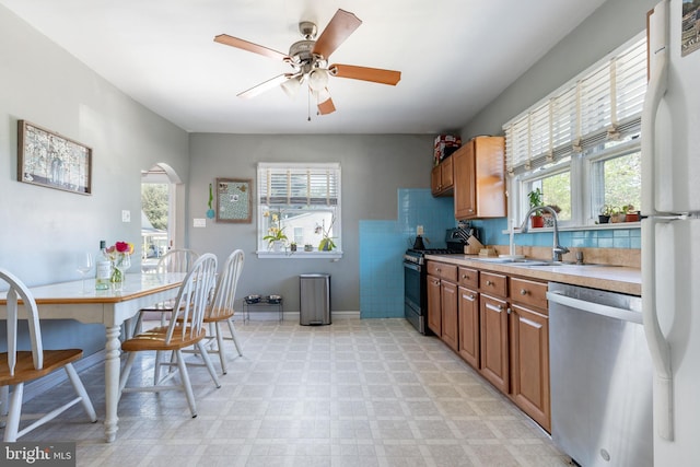 kitchen featuring a healthy amount of sunlight, light floors, range with gas cooktop, a sink, and dishwasher