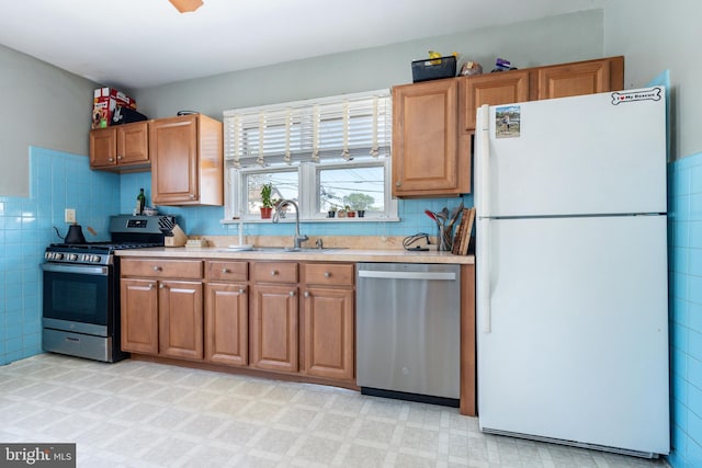 kitchen with light countertops, stainless steel appliances, brown cabinets, and a sink
