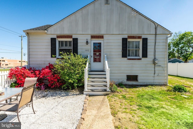 bungalow-style home with fence, a shingled roof, a patio area, and a front yard