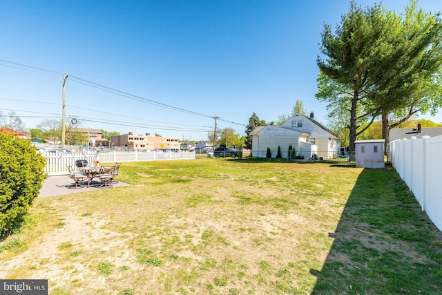 view of yard featuring a storage shed, an outbuilding, a fenced backyard, and a patio area