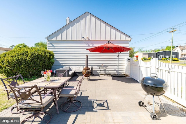 view of patio featuring fence, a gate, outdoor dining space, and area for grilling
