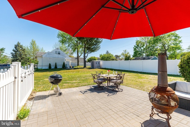 view of patio / terrace with a storage shed, a fenced backyard, outdoor dining area, an outdoor structure, and a grill