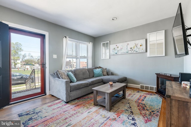 living room featuring baseboards, visible vents, and wood finished floors