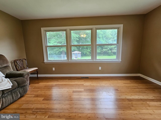 living area featuring healthy amount of natural light, light wood-style floors, and baseboards