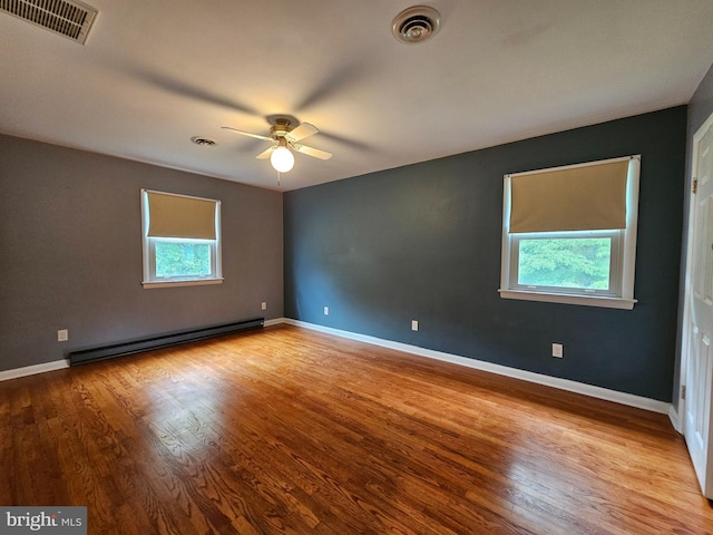 empty room featuring a baseboard heating unit, a ceiling fan, wood finished floors, and baseboards