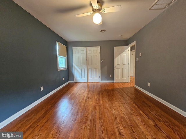 unfurnished bedroom with wood finished floors, baseboards, a closet, and a ceiling fan