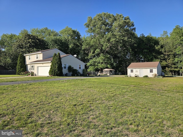 view of green lawn featuring asphalt driveway and a garage