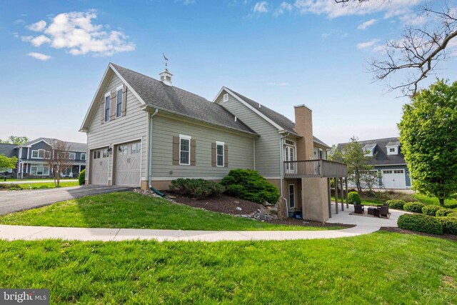view of side of property featuring a lawn, a garage, a patio area, and aphalt driveway