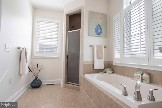 bathroom featuring tile patterned floors, a shower stall, a bath, and baseboards