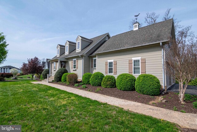 view of front of home featuring a front yard and a shingled roof