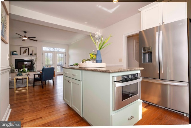 kitchen featuring white cabinets, stainless steel appliances, a center island, light stone countertops, and light wood finished floors
