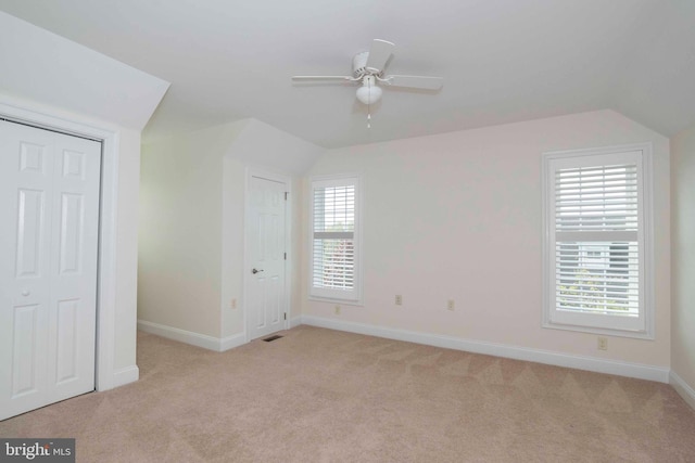 unfurnished bedroom featuring vaulted ceiling, light colored carpet, and baseboards