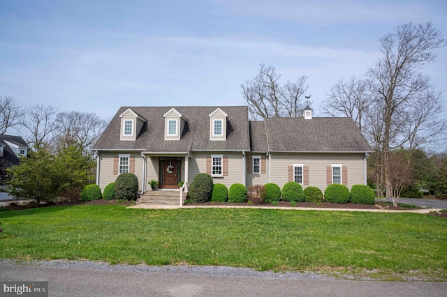 cape cod-style house with a chimney, a front yard, and a shingled roof