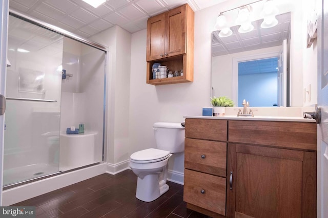 bathroom with a shower stall, vanity, toilet, baseboards, and wood finished floors