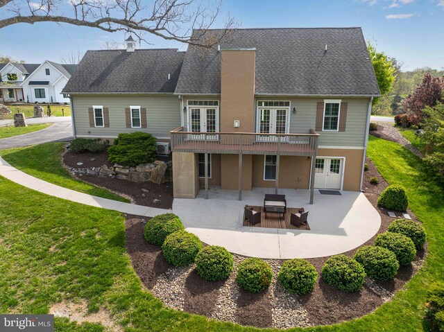 rear view of house featuring a patio, a yard, roof with shingles, a deck, and french doors
