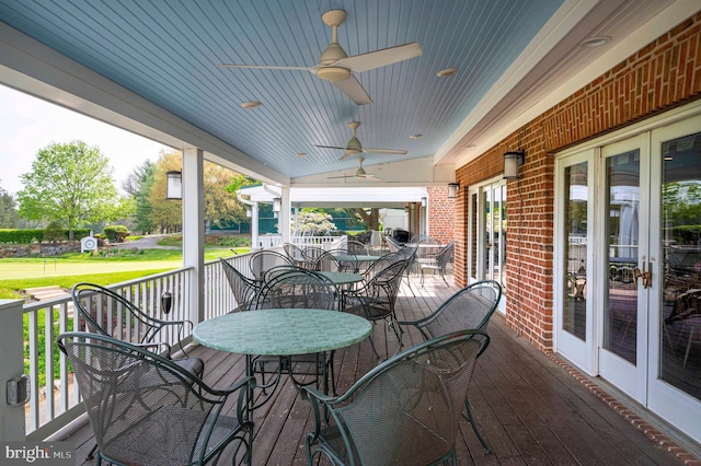 wooden terrace featuring ceiling fan, french doors, outdoor dining space, and covered porch