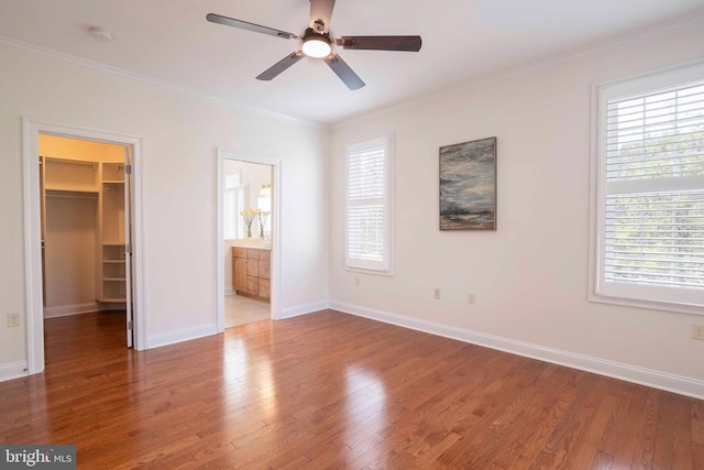 unfurnished bedroom with a spacious closet, wood finished floors, and multiple windows