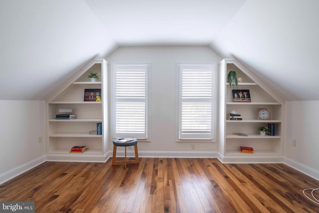 additional living space with hardwood / wood-style flooring, baseboards, vaulted ceiling, and built in shelves
