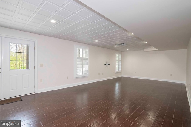 unfurnished living room featuring dark wood finished floors, baseboards, and a wealth of natural light