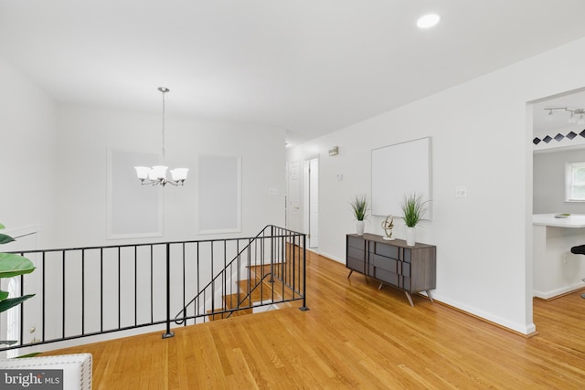 hallway featuring an upstairs landing, a chandelier, wood finished floors, and baseboards