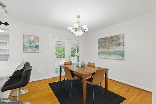 dining area with a chandelier, light wood-style flooring, and healthy amount of natural light