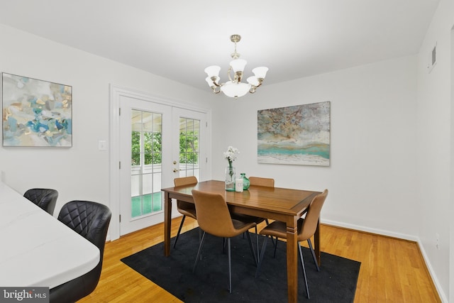 dining area with a chandelier, french doors, light wood-style flooring, and baseboards