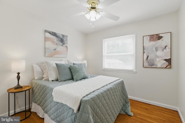 bedroom featuring baseboards, wood finished floors, and a ceiling fan