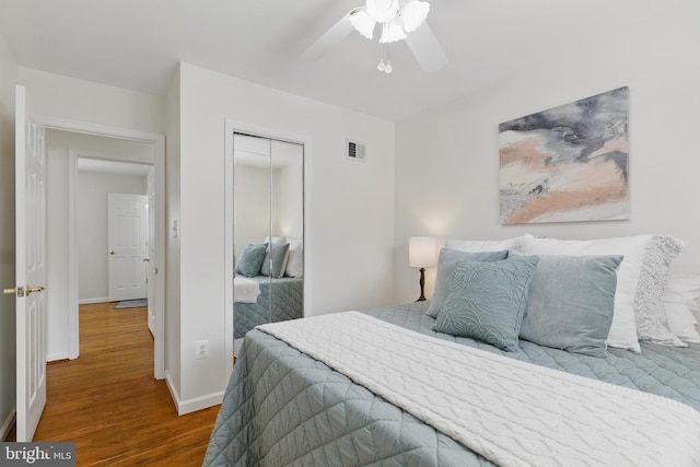 bedroom featuring wood finished floors, a closet, baseboards, and a ceiling fan