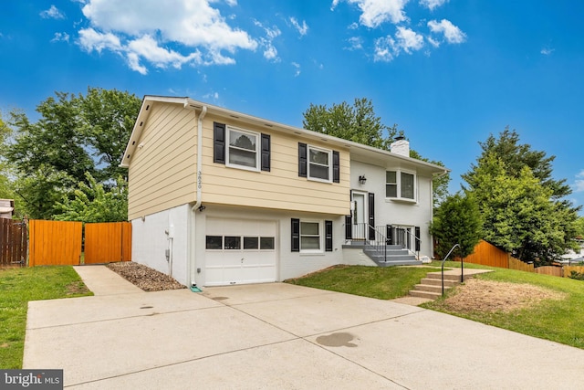 bi-level home with a garage, a chimney, driveway, and a gate