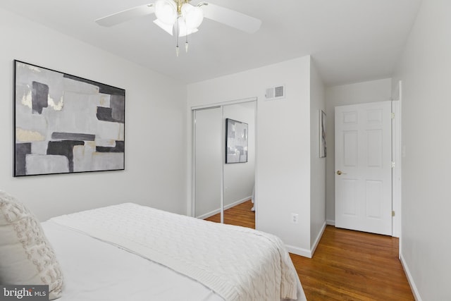 bedroom featuring wood finished floors, a closet, baseboards, and ceiling fan