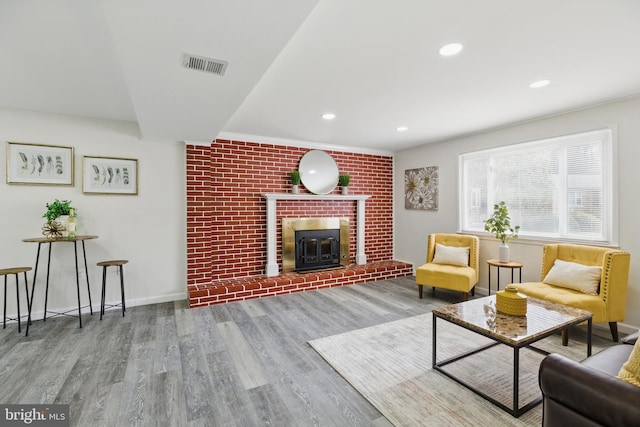 living area with wood finished floors, a brick fireplace, recessed lighting, and baseboards
