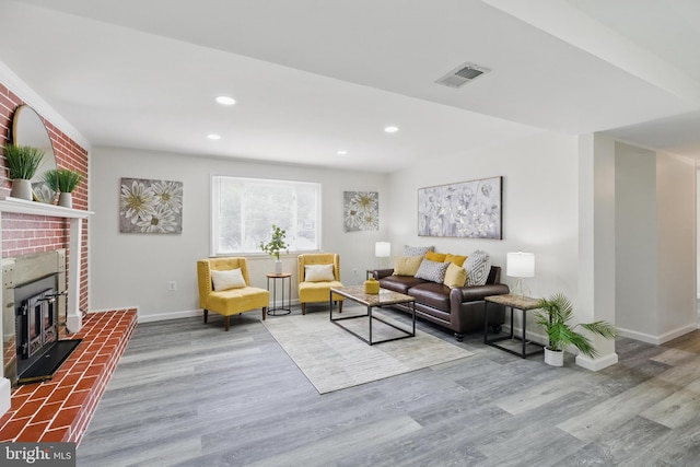 living area with wood finished floors, baseboards, recessed lighting, and a fireplace