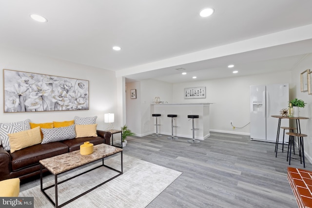 living area featuring a bar, wood finished floors, recessed lighting, and baseboards
