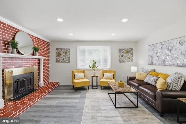 living area featuring wood finished floors, a brick fireplace, recessed lighting, and baseboards