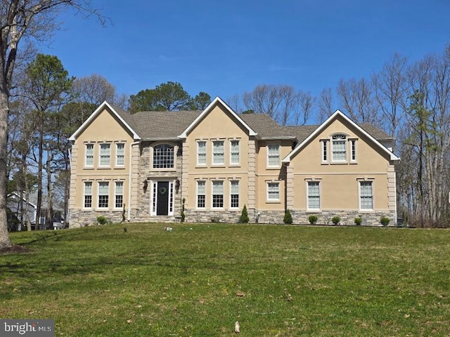 view of front facade featuring stucco siding, a front yard, and stone siding