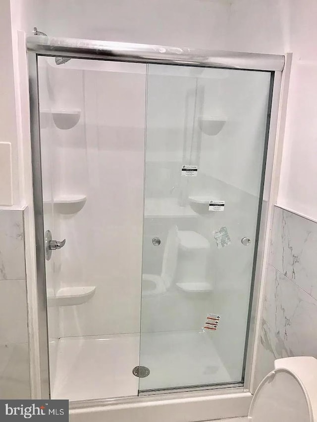 full bathroom featuring toilet and a shower stall