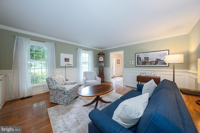 living room featuring visible vents, wood finished floors, wainscoting, and ornamental molding