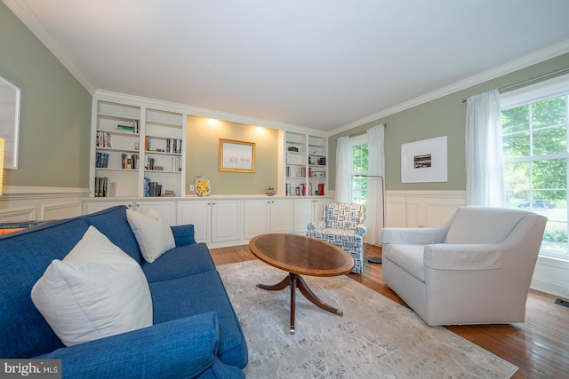 living room featuring crown molding, wood finished floors, a healthy amount of sunlight, and built in features