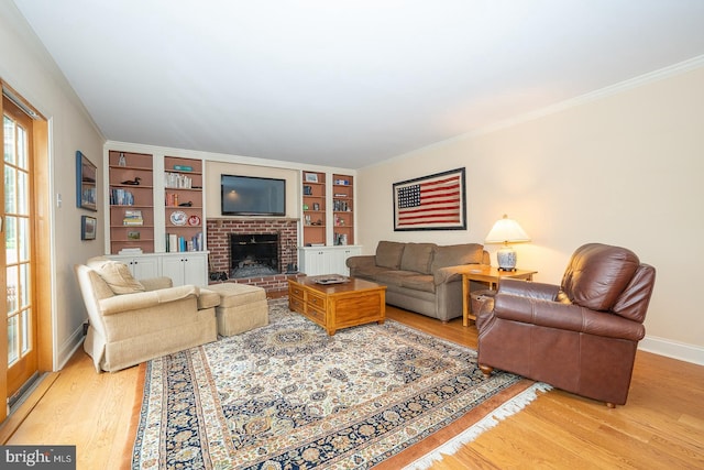 living area with baseboards, a brick fireplace, light wood finished floors, and built in shelves