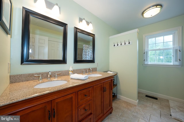 full bath with double vanity, visible vents, baseboards, and a sink