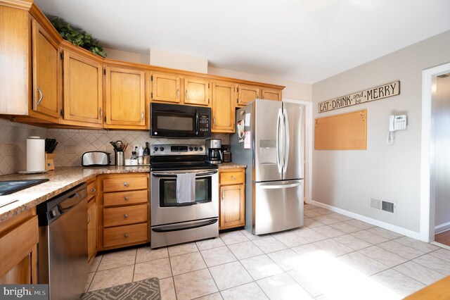 kitchen featuring light stone countertops, decorative backsplash, visible vents, baseboards, and appliances with stainless steel finishes