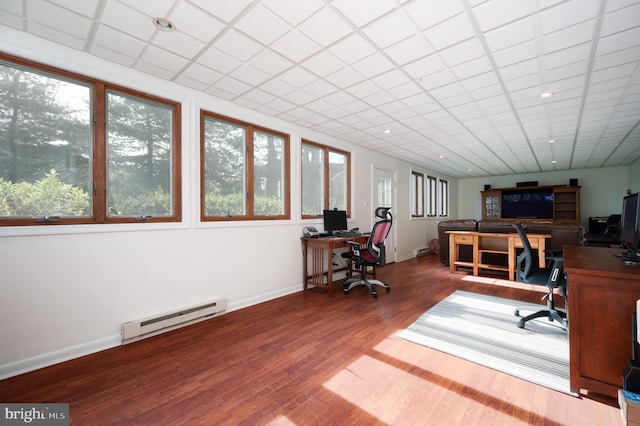 office space with a healthy amount of sunlight, baseboards, wood finished floors, and a baseboard heating unit